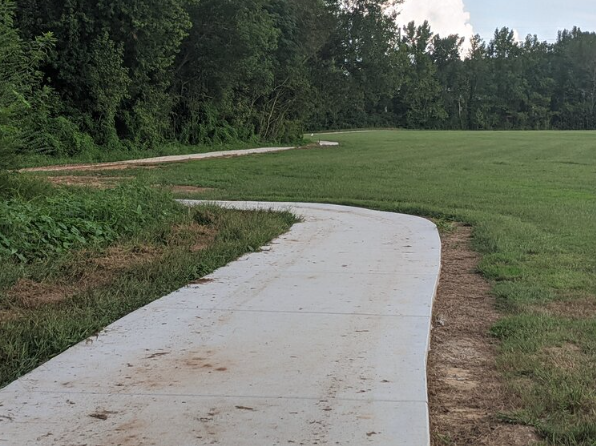 WatereeRiverVeteransPark WatereeVeteransPark paved trail winding around a lawn of green grass at Wateree River Veterans Park