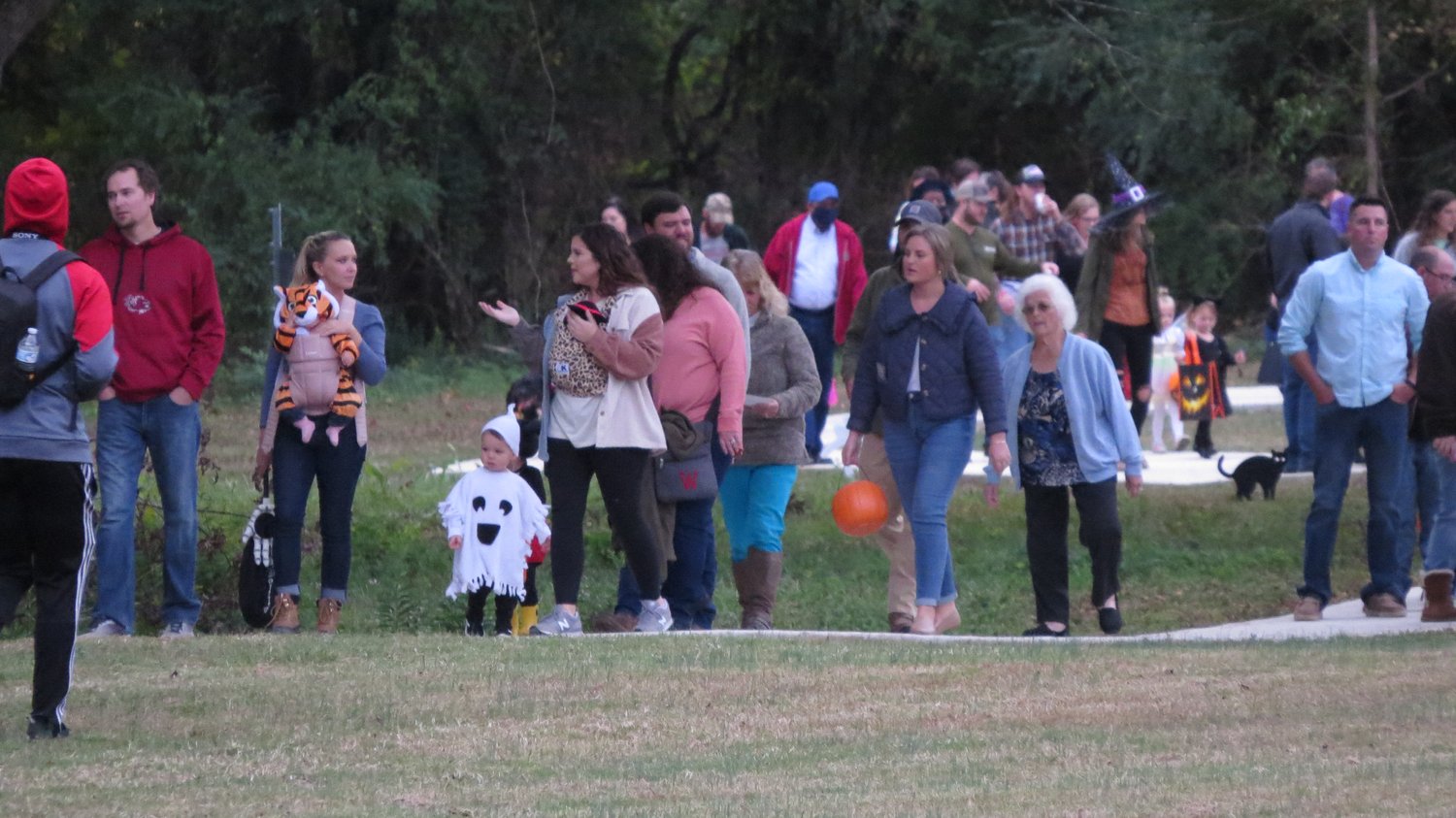 A close up of adults with their children Trick or Treating at Veterans Park Loop Trail